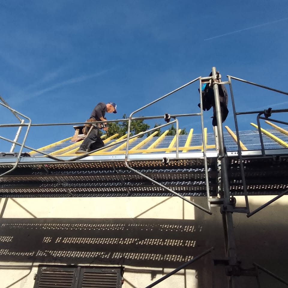 Charpentiers sur échafaudage posant le lattage d'une toiture